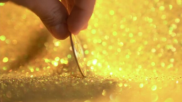 Bitcoin on a shiny gold background in slow motion.Female fingers in close-up turn the bitcoin coin around its axis. High quality FullHD footage