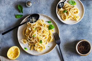 vegetarian pasta  with lemon, basil, parmesan and black pepper searved on a gray stone background. top view with copy space.