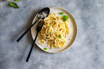 vegetarian pasta  with lemon, basil, parmesan and black pepper searved on a gray stone background. top view with copy space.