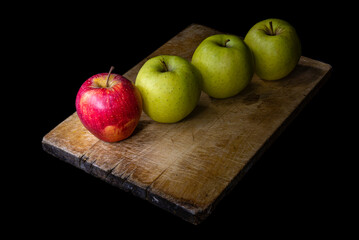 Still life of yellow and red apples on wooden cutting board