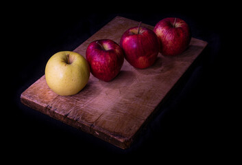 Still life of red and yellow apples on wooden cutting board