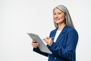 Female mature auditor inspector examiner controller in formal wear writing on clipboard, checking the quality of goods and service looking at camera isolated in white background