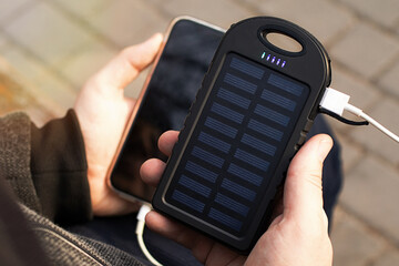 Closeup photography of man's hands,holding mobile phone and solar powerbank.