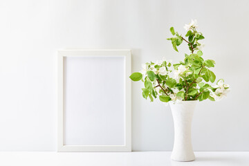 Home interior with decor elements. Mockup with a white frame and spring flowers in a vase on a white table