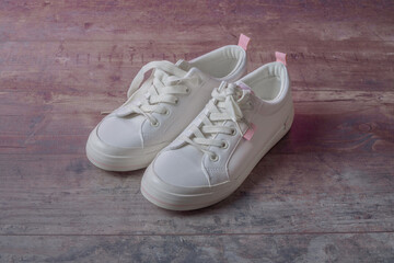 Fototapeta na wymiar Children's sneakers are white with pink details. On a textured background