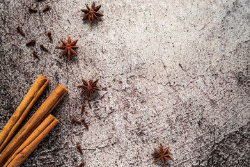 spicy aromatic spices, cinnamon sticks, cloves and star anise on a gray neutral background