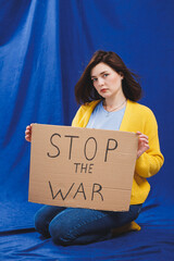 A Ukrainian woman in a yellow sweater and blue jeans with a stop the war sign. Ukrainian girl...