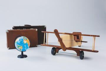 Wooden plane, world globe, brown suitcases. Travel around the world