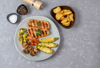 Serving of grilled chicken with vegetable garnish and potatoes. BBQ food background, copy space