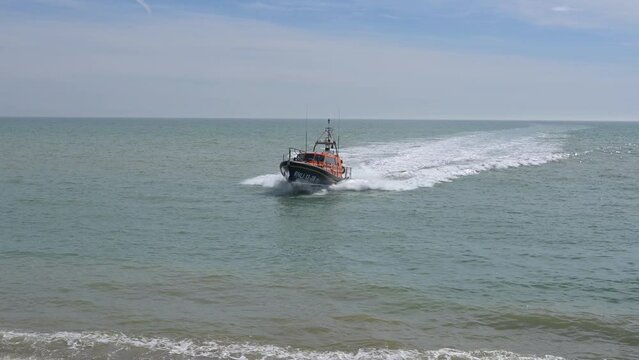 The RNLI Shannon Class Lifeboat based at Hastings approaching the beach at speed and driving onto the shingle beach.