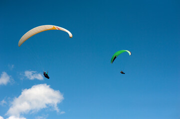 Two paragliders flying in the blue sky against the background of clouds. Paragliding in the sky on a sunny day.