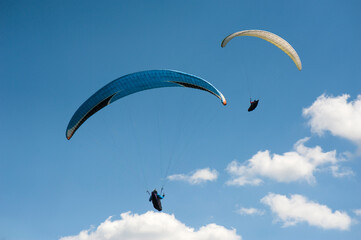 Two paragliders flying in the blue sky against the background of clouds. Paragliding in the sky on...