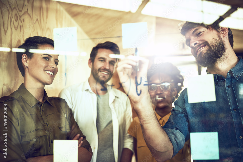 Fototapete Theres no problem too hard for them to solve. Shot of a group of businesspeople brainstorming with notes on a glass wall.