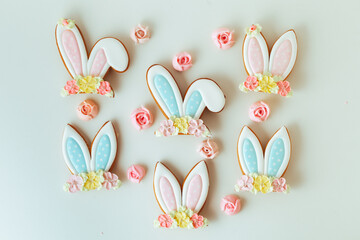 Gingerbread cookies in the shape of cute Easter bunny ears decorated with festive icing and flowers on the white background. Flat lay