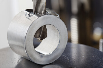 metal drill bit make holes in aluminium pipe on industrial drilling machine. Metal work industry.