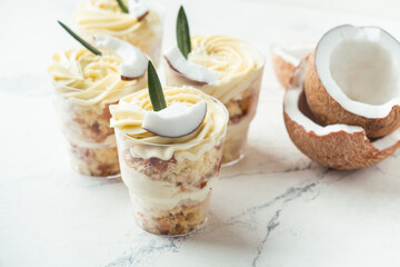 English layered dessert trifle of buscuit dough, custard and whipped cream with fresh coconut pieces on the white background
