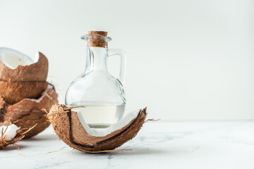 Cracked coconut with coconut oil in glass bottle on the white background