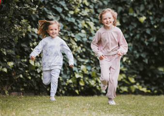 Naklejka na ściany i meble Childhood isnt forever but happy memories are. Shot of two adorable little girls having fun in a garden.