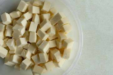 Paneer or Indian cottage cheese, cheese common in the Indian subcontinent made from cow or buffalo milk, is diced in cubes in a plastic bowl.