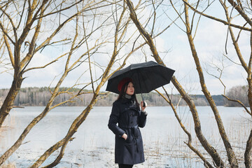 Portrait of a young nice woman with black umbrella outdoors