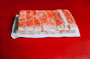 A large package of frozen crab sticks, fish meat lies on a red background. Food photography, concept.