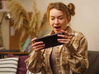A happy girl plays a fun adventure video game on a portable game console with her teenage friends. Prizes, win, fun, virtual reality, cyberspace, youth culture.
