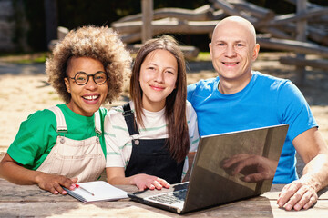 Diverse ethnic family looking at laptop outside.