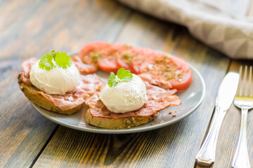 poached eggs served on toast with bacon and tomato and herbs