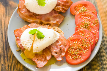 poached eggs served on toast with bacon and tomato and herbs