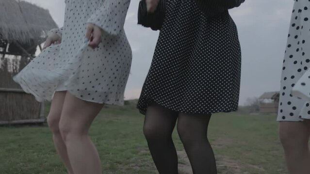 girls in short dresses dancing on the grass in nature, close-up