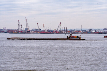 Fototapeta premium Tugboats moving barges in New York Harbor with the New York Skyline in the background.