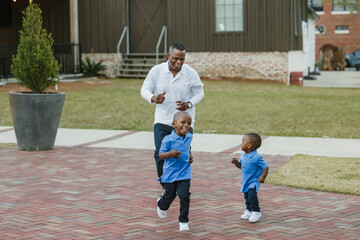 A dad chasing his two sons outdoors while they are playing together and bonding