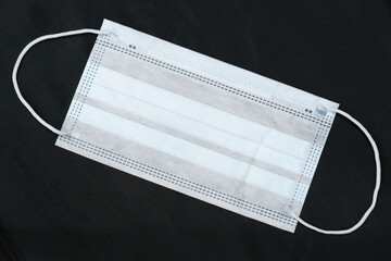 Medical mask on a black background. Gauze dressing as a means of combating and preventing airborne diseases.