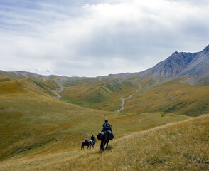 Fototapeta na wymiar Riders with weapons on three horses move in mountainous terrain.