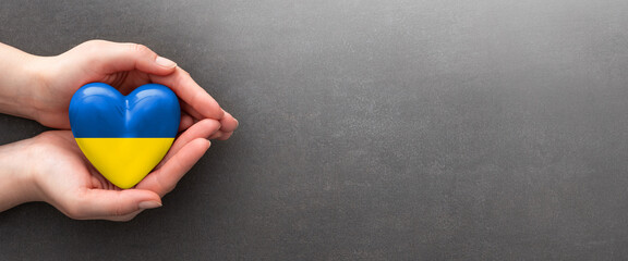 The woman is holding a Ukraine heart.