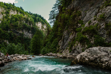 Mountain river with green water is running among tree covered cliffs in the gorge. Shot in Abkhazia