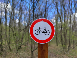 Road sign prohibiting bicycles entering the blurred forest in the background.