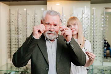 an elderly man with an ophthalmologist chooses glasses in the optics salon.
