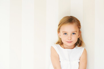 Portrait of adorable little girl with blue eyes wearing white dress