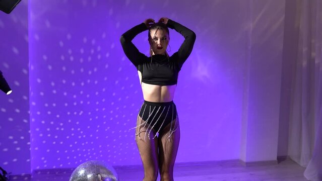 A girl dancing on the multicolored lights neon of the studio. Slow-motion