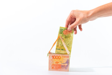 hand putting a bill in a house, white background, economics concept, invest in the house, saving