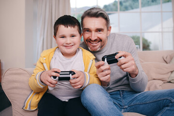 Never a sore loser. Shot of a father and son playing video games while bonding on the couch at home.