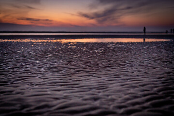 Plaża po zachodzie słońca, niebo odbijające się w wodzie. Morski krajobraz wieczorem.