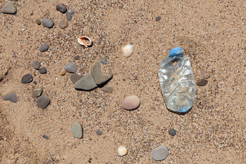 Plastic garbage on the beach. Single-use plastic bottle thrown by sea wave on shore. Concept - Pollution of world ocean by household waste