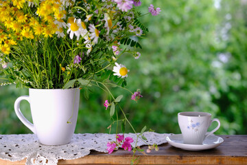cup of tea, beautiful summer bouquet of wildflowers, handmade lace white doily on the table, summer time concept, tea drinking in the garden