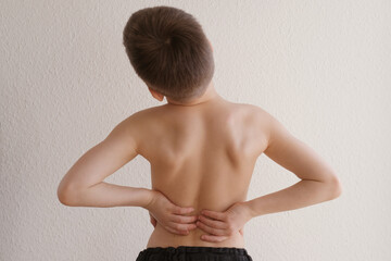 naked back of boy, child 8-10 years old grabbed a sore spot, curved spine, pain in spine, concept...