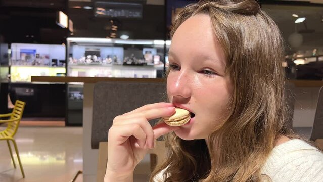 Teenage girl brown-haired woman with a mole above her lip eats makarun close-up slowly biting it off and blows with pleasure. High quality 4k footage
