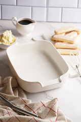 Step by step process of preparing italian dessert tiramisu out of ladyfinger biscuits, mascarpone cheese, espresso on white marble background