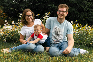 mom and dad play with their son in the garden in the village