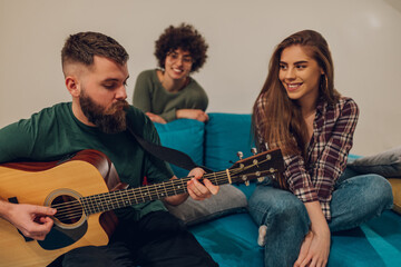 Friends playing guitar and singing songs while having party at home